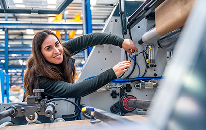 Person justiert Kabel an CNC-Industrieanlage in heller Produktionshalle