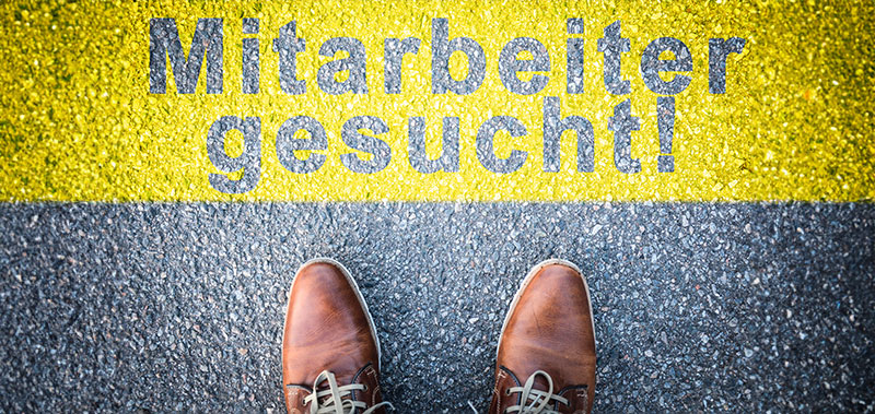 Schuhe stehen vor einer Markierung mit der Aufschrift Mitarbeiter gesucht