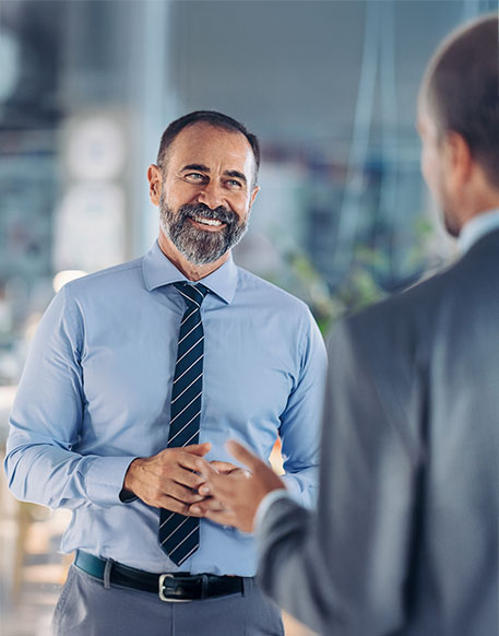 Zwei M&auml;nner f&uuml;hren Gespr&auml;ch im modernen B&uuml;ro, einer gestikuliert, einer h&ouml;rt zu