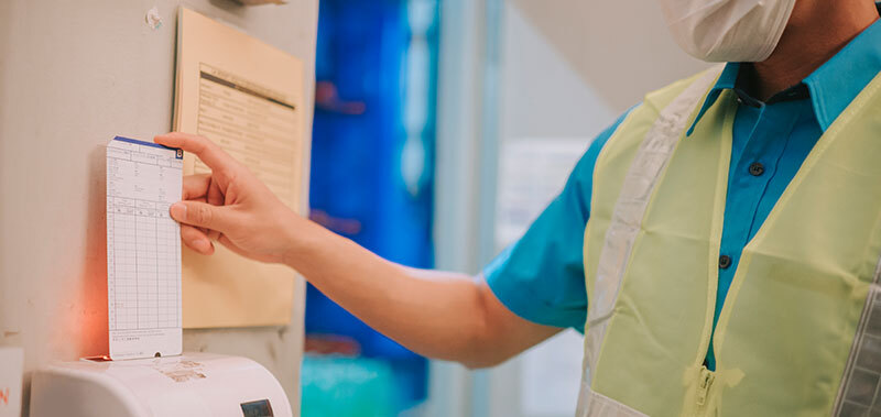 Person stempelt Arbeitszeit an einer Zeiterfassungsmaschine