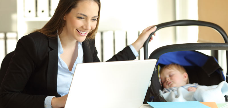 Frau arbeitet am Laptop, neben ihr schl&auml;ft ein Baby im Kinderwagen