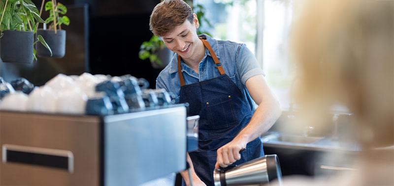 Junger Mann arbeitet als Barista und bereitet Kaffee zu